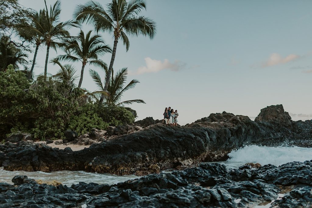 Family standing on lava rock on beach