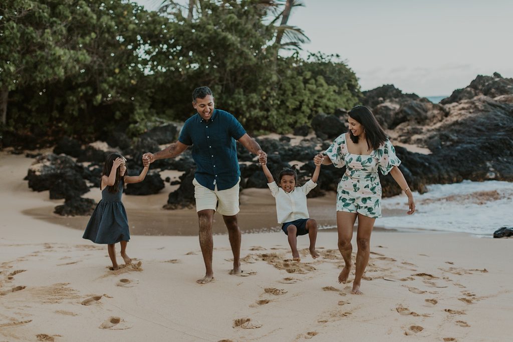 Family holding hands and having fun walking on the beach