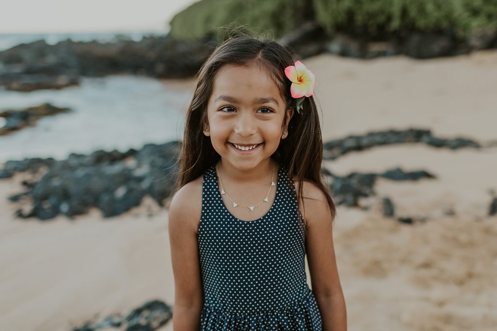 Individual portrait of daughter on beach with tropical flower in hair