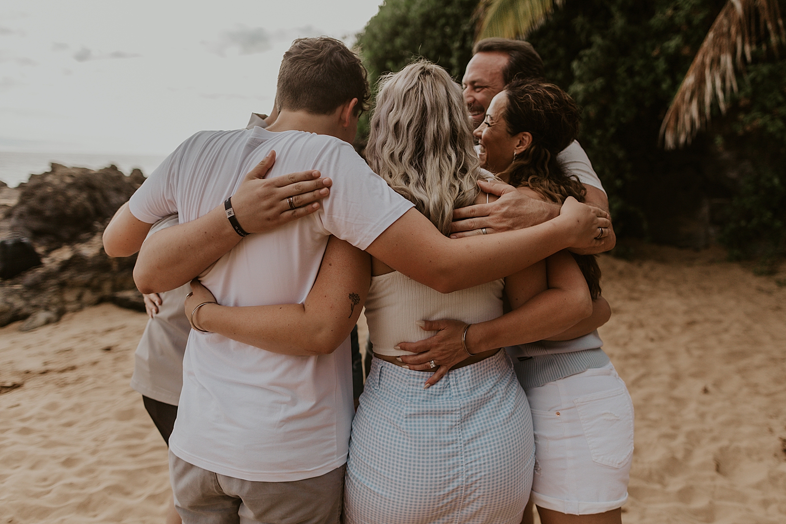 Entire grown up family arms wrapped around each other in a circle on the Po’olenalena beach