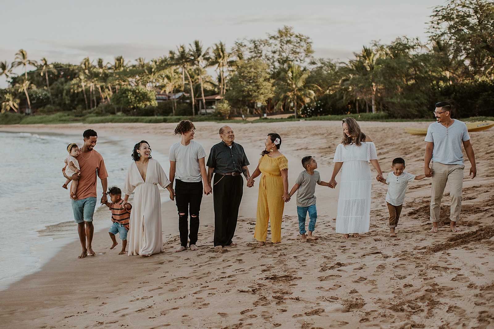 Entire multigenerational family standing holding hands on the beach together