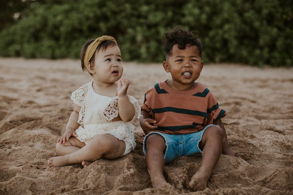 Little kids sitting on the sand