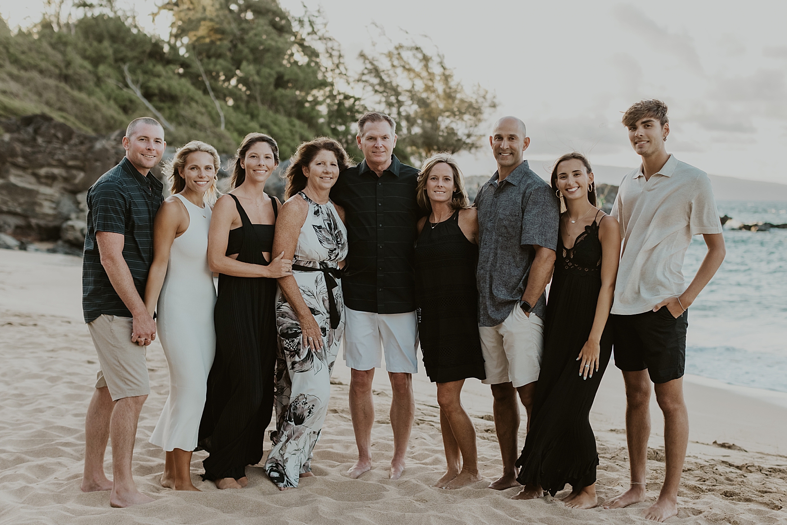 Full family portrait with everyone arm around each other standing on the beach