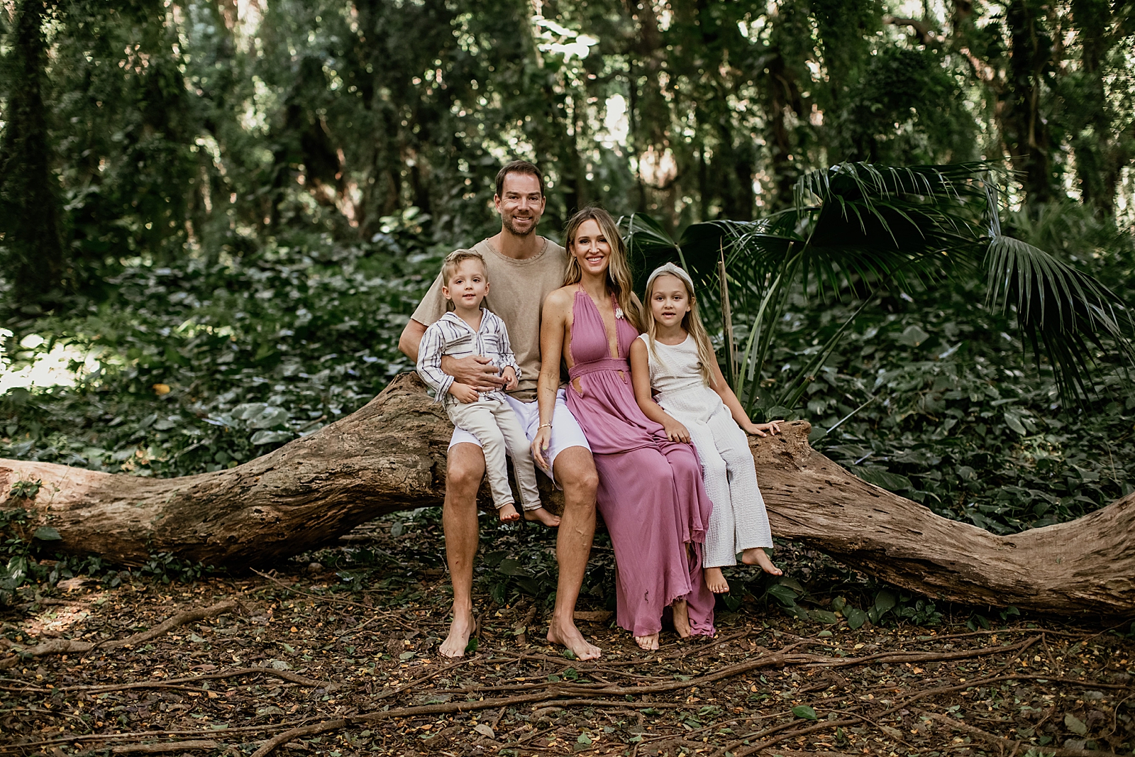 Family sitting together on fallen tree in the forest