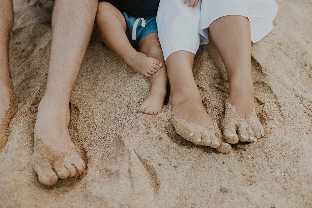 Closeup of parents and child's feet in the sand